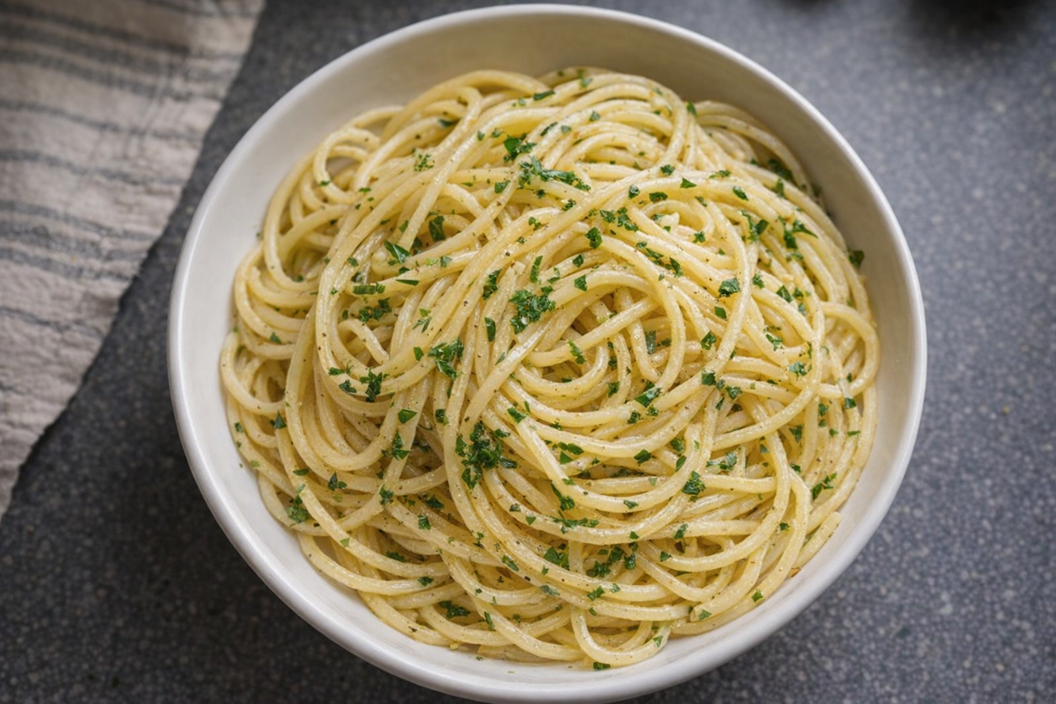 A top-down, studio-lit shot of perfectly cooked spaghetti in a white bowl, lightly tossed with olive oil and parsley, ready to be served